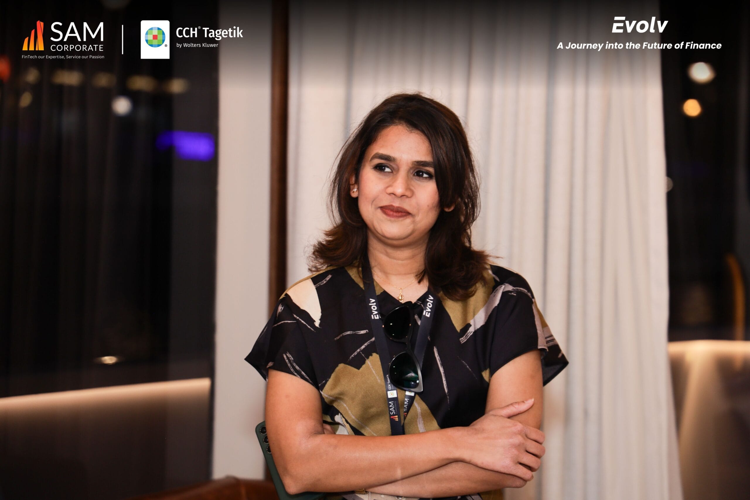 Woman networking at the Evolv' event with SAM Corporate and CCH Tagetik branding.