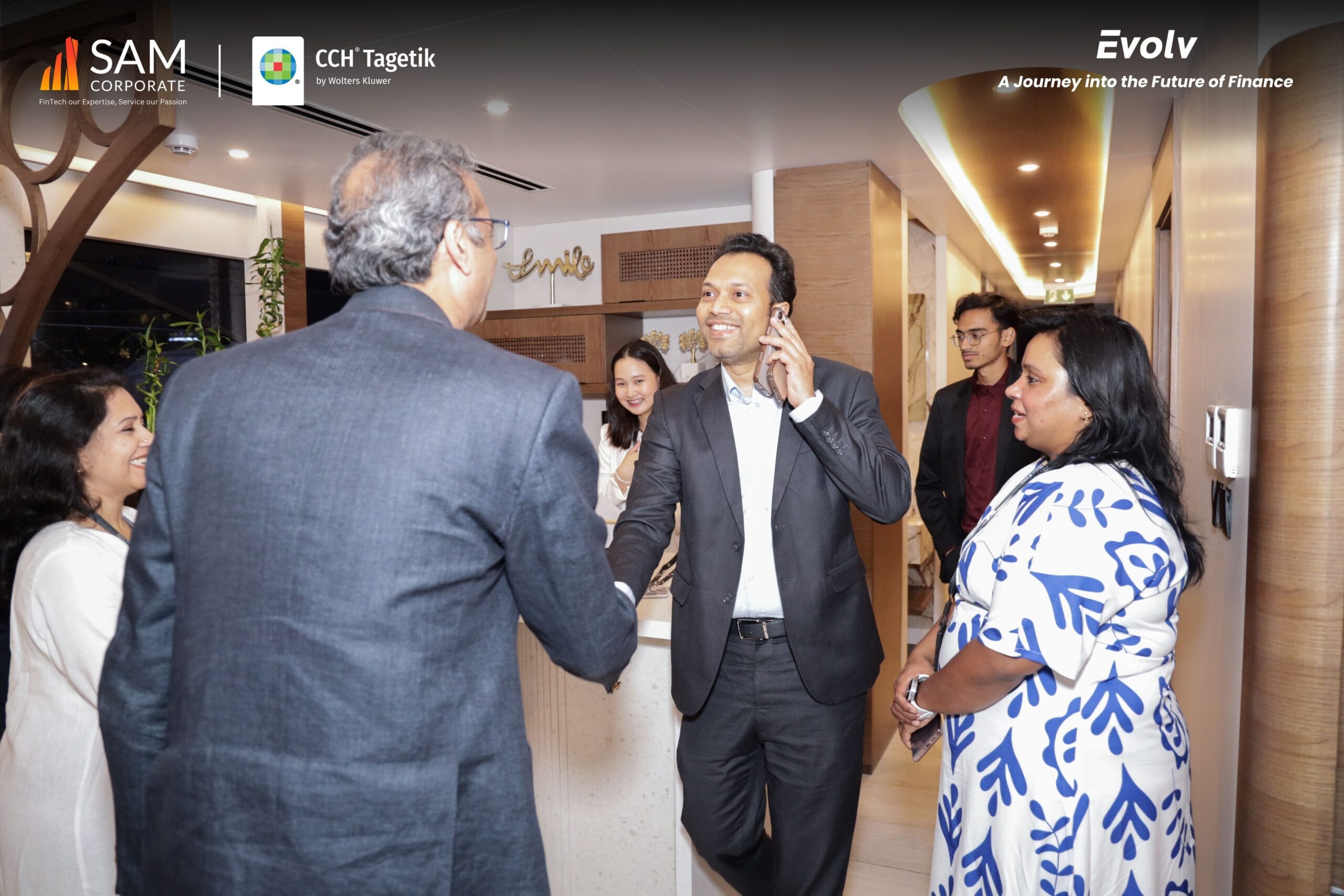Executives networking with a handshake at the Evolv event, highlighting the partnership between SAM Corporate and CCH Tagetik.