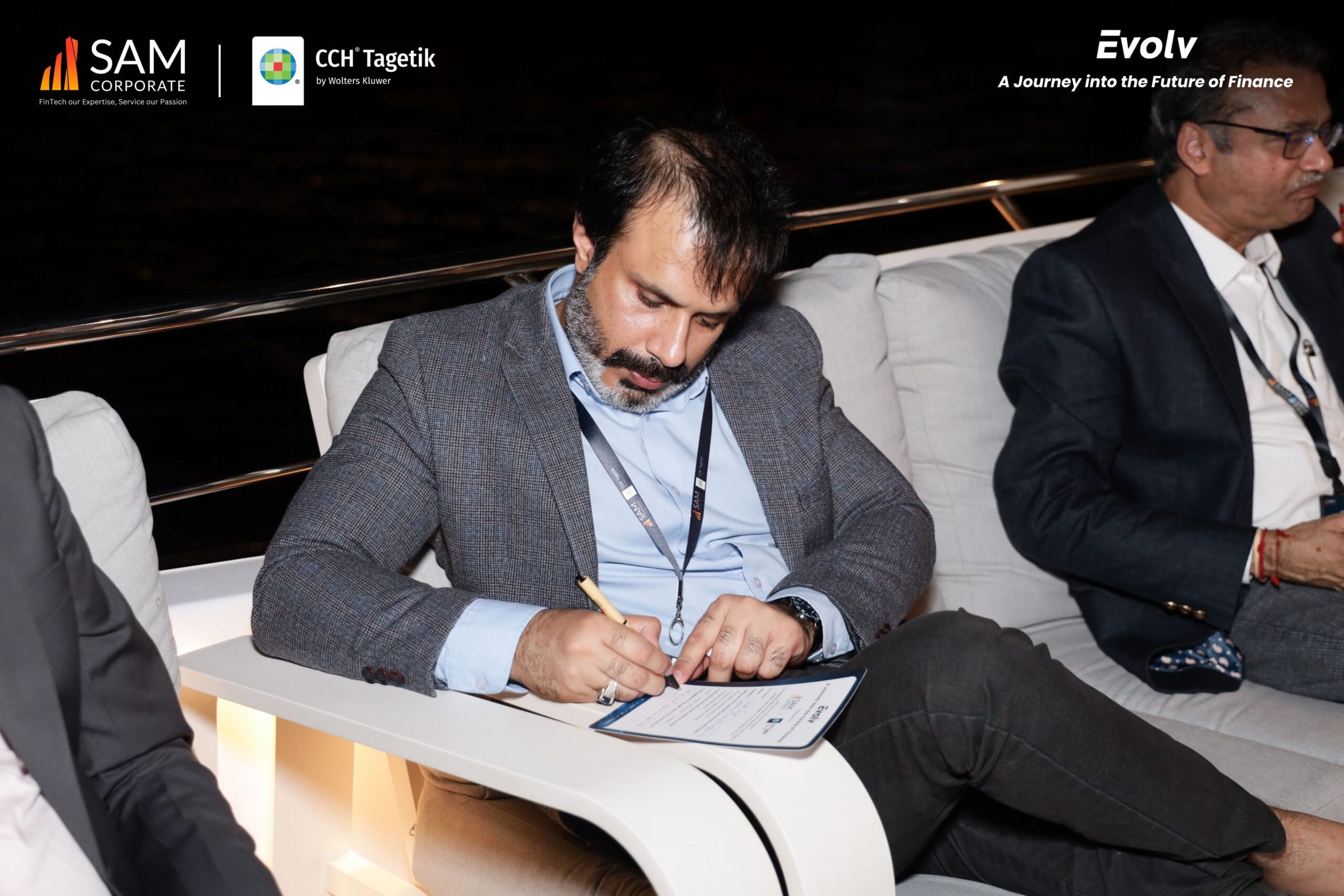 A focused executive providing feedback on a survey while seated at the Evolv networking event hosted by SAM Corporate and CCH Tagetik.