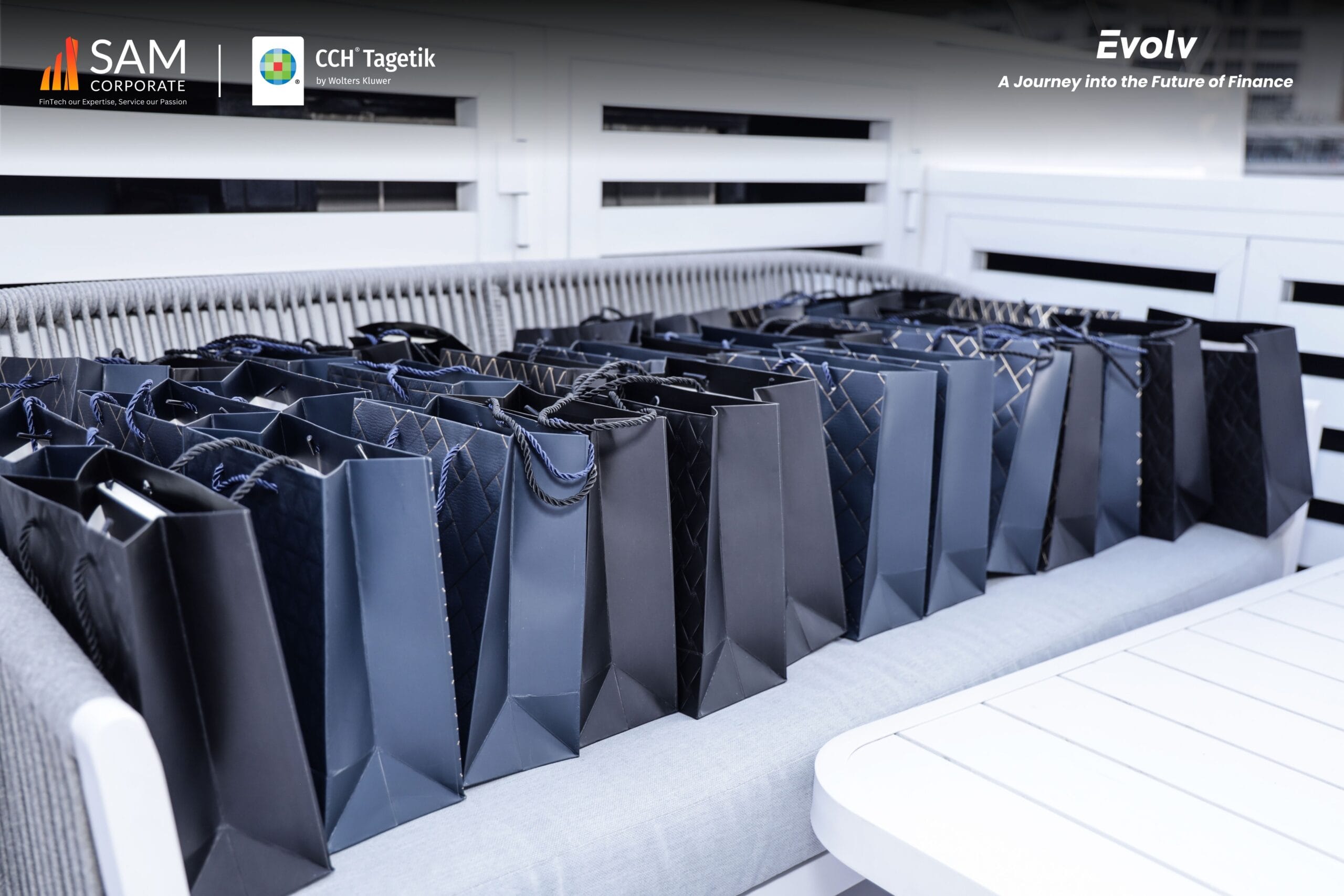 Row of corporate gift bags for attendees of the Evolv summit by SAM Corporate and CCH Tagetik.