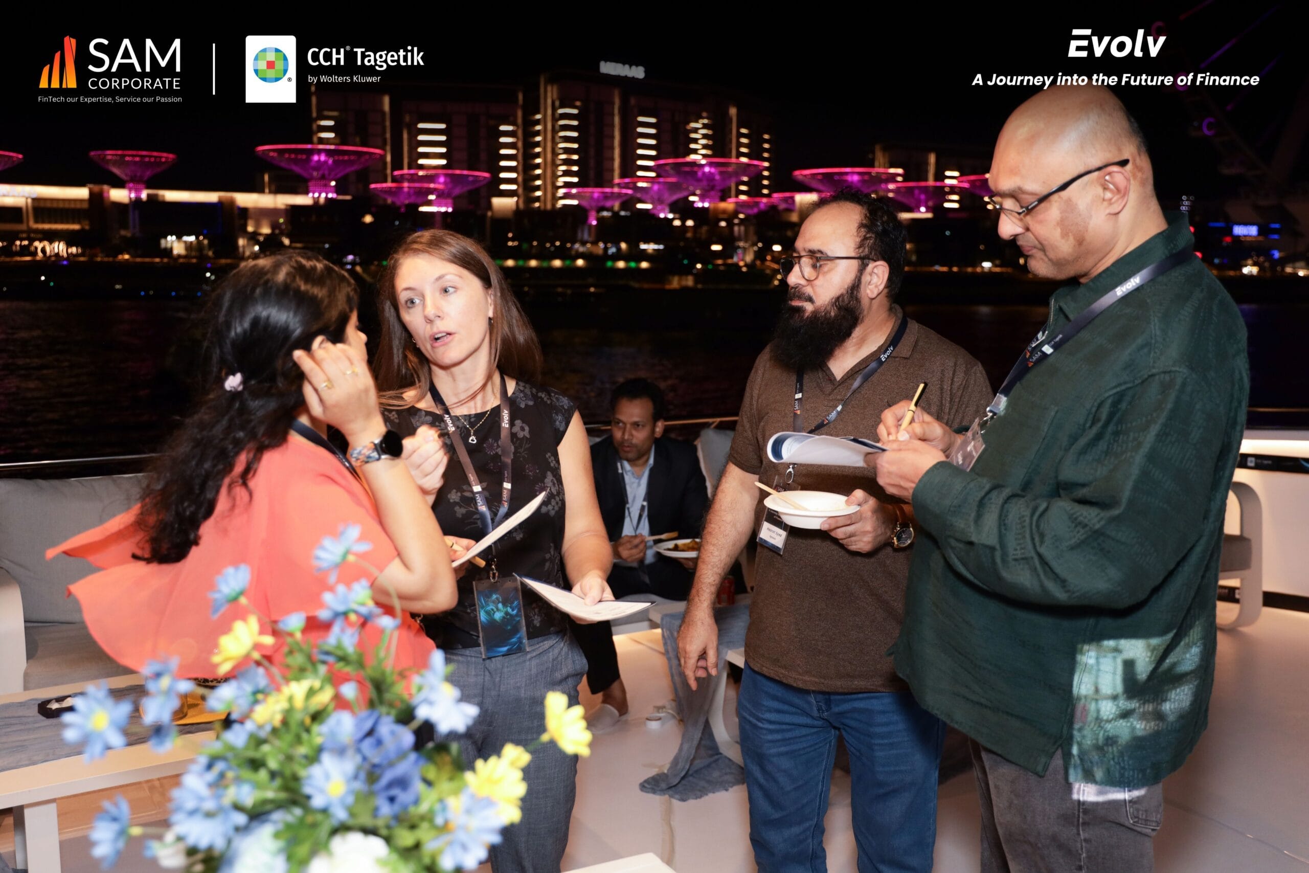 SAM Corporate and CCH Tagetik executives and guests networking on the yacht deck with the illuminated cityscape in the background at the Evolv event.