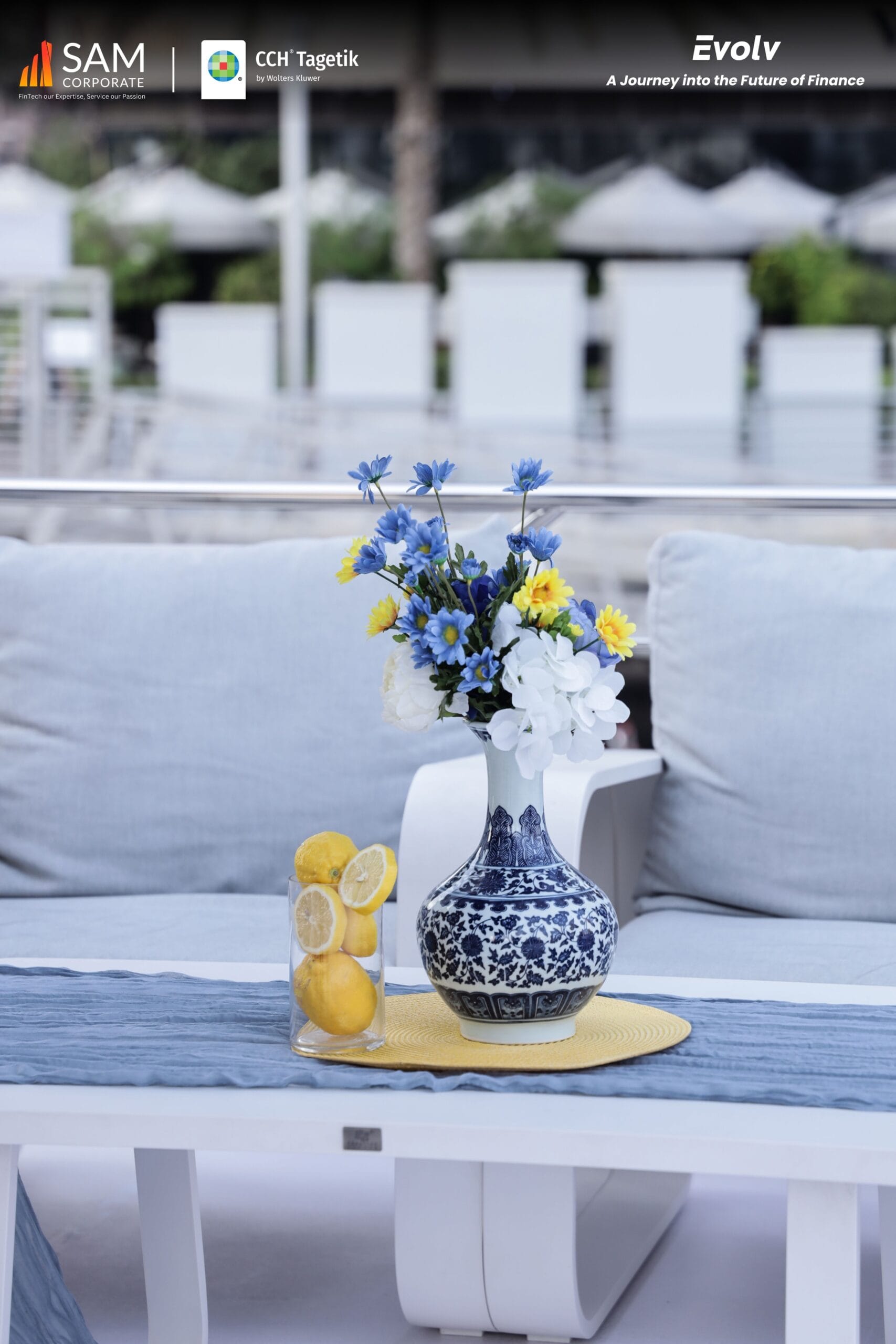 A still life shot of the beautiful decor, featuring a vase of blue and yellow flowers and fresh lemons, used at the Evolv event hosted by SAM Corporate and CCH Tagetik.