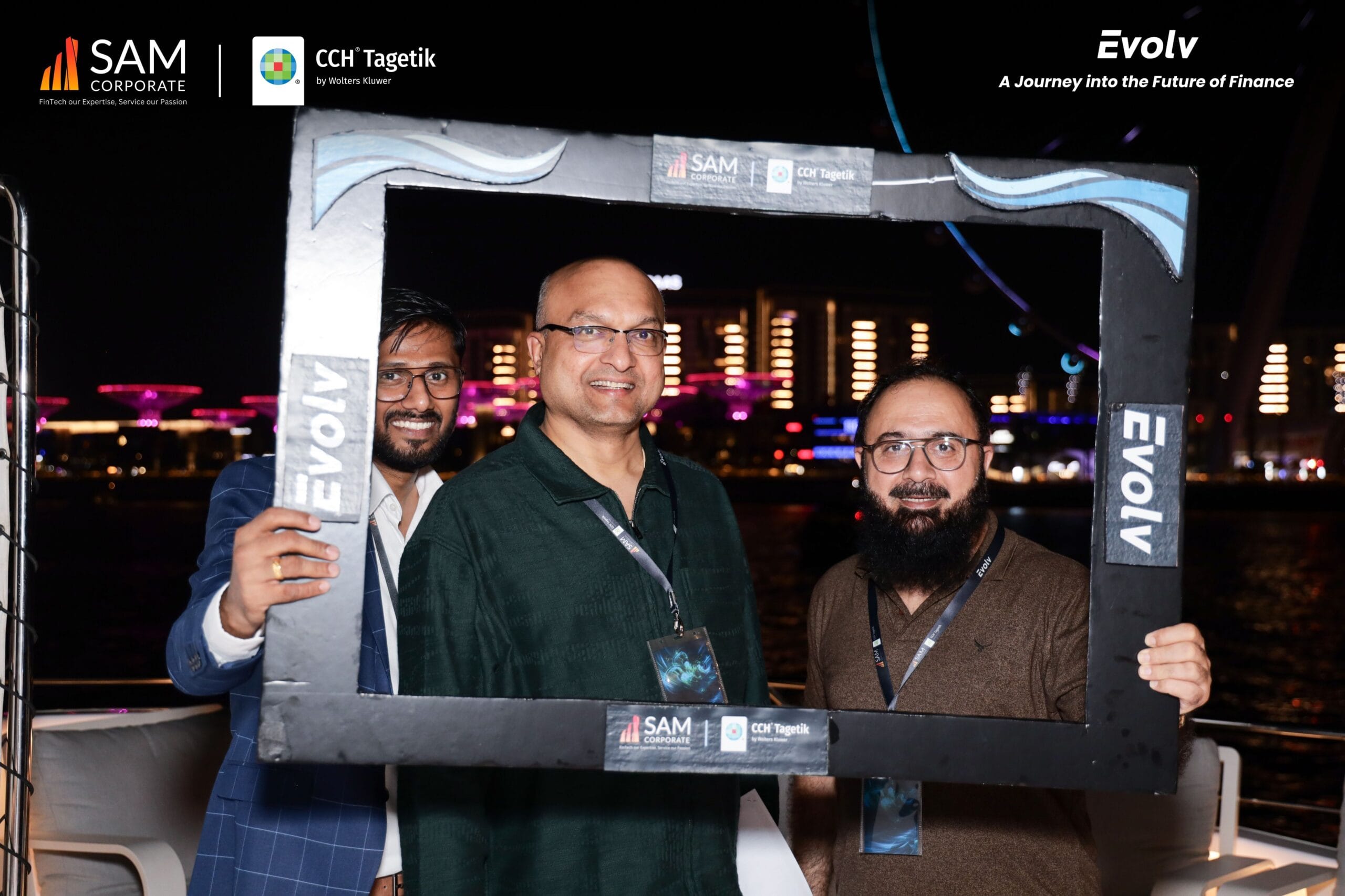 Three SAM Corporate and CCH Tagetik executives smiling in a photo booth on the yacht during the Evolv networking event.