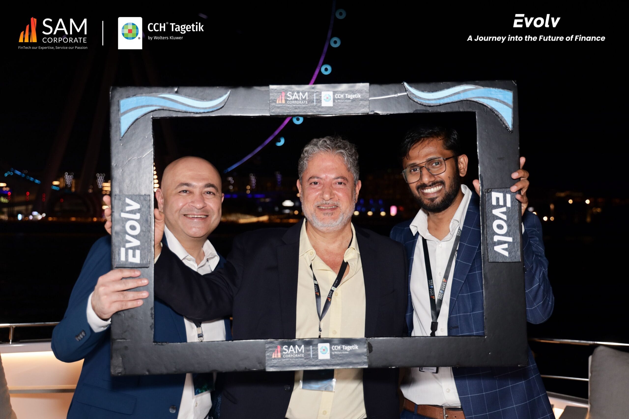 Three SAM Corporate and CCH Tagetik executives smiling in a photo booth on the yacht during the Evolv networking event.