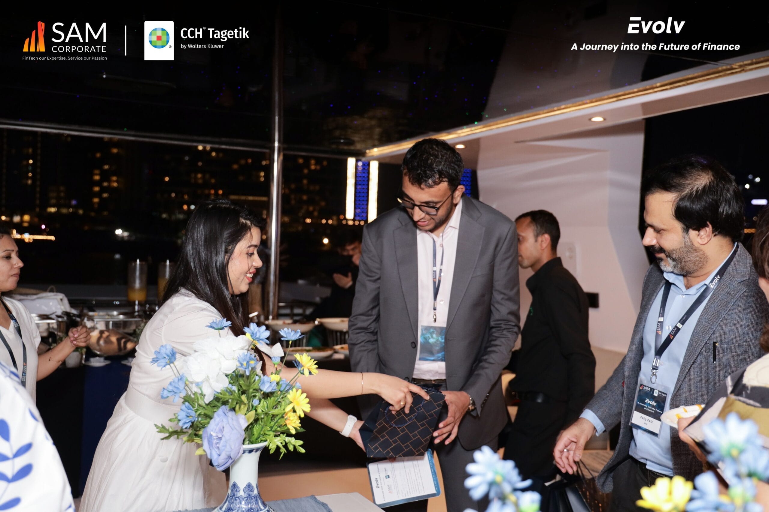 A smiling executive from SAM Corporate or CCH Tagetik presenting a gift to a guest at the Evolv event.