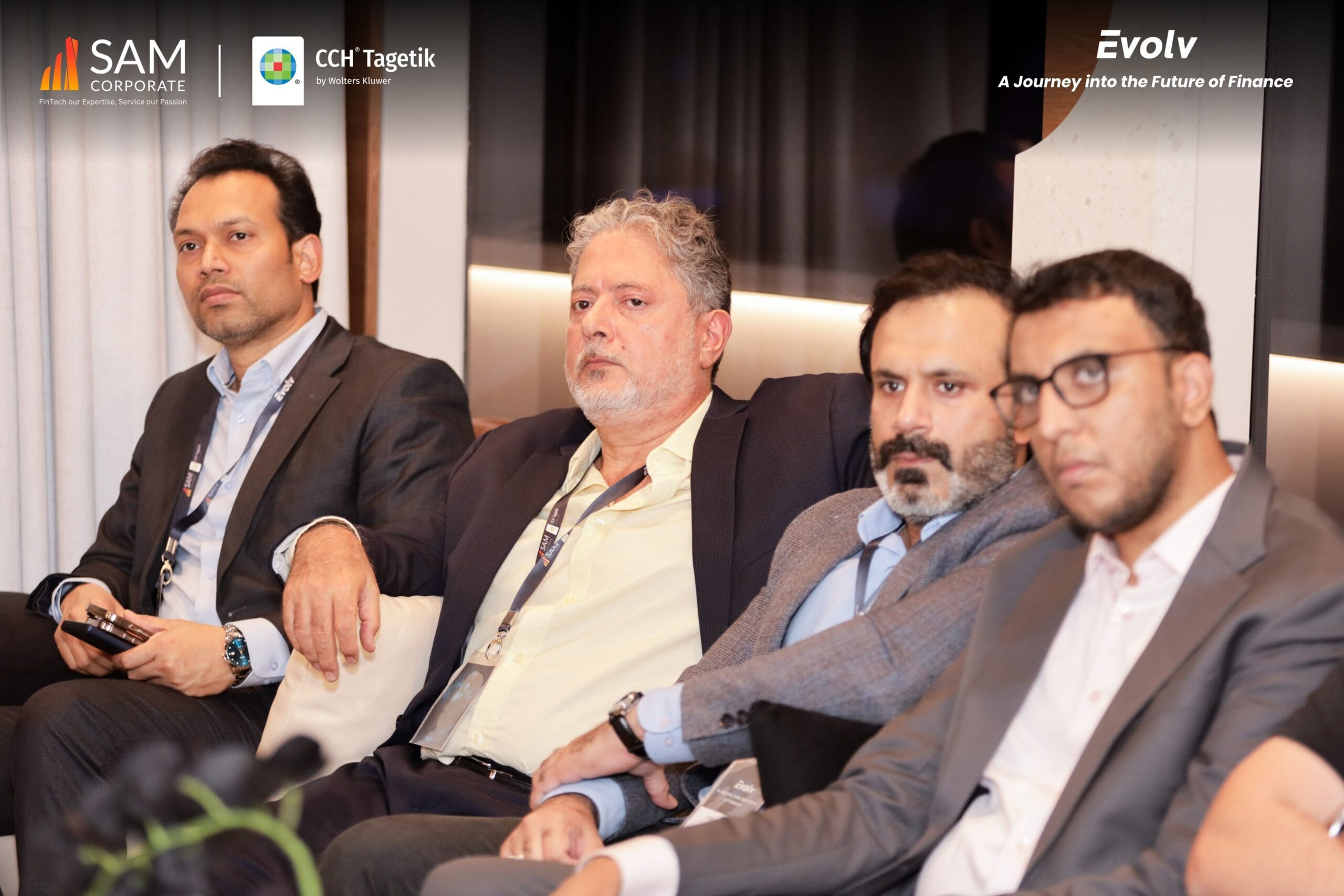Four male executives seated attentively during a presentation at the Evolv event by SAM Corporate and CCH Tagetik.