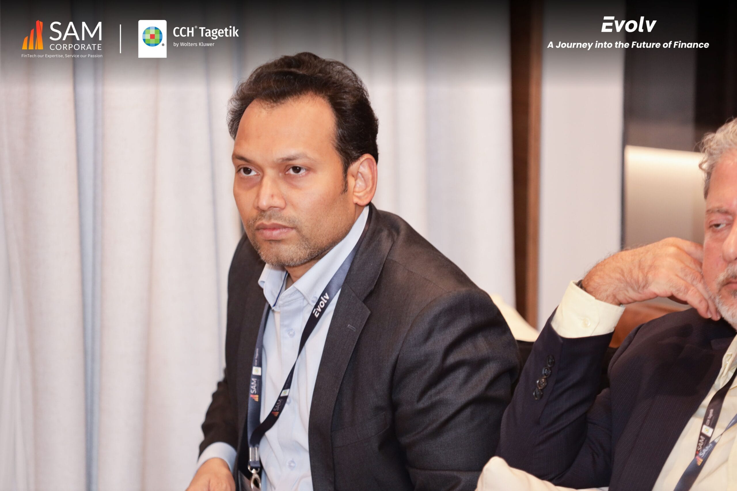 Two male finance executives seated, listening to a presentation at the Evolv event by SAM Corporate and CCH Tagetik.