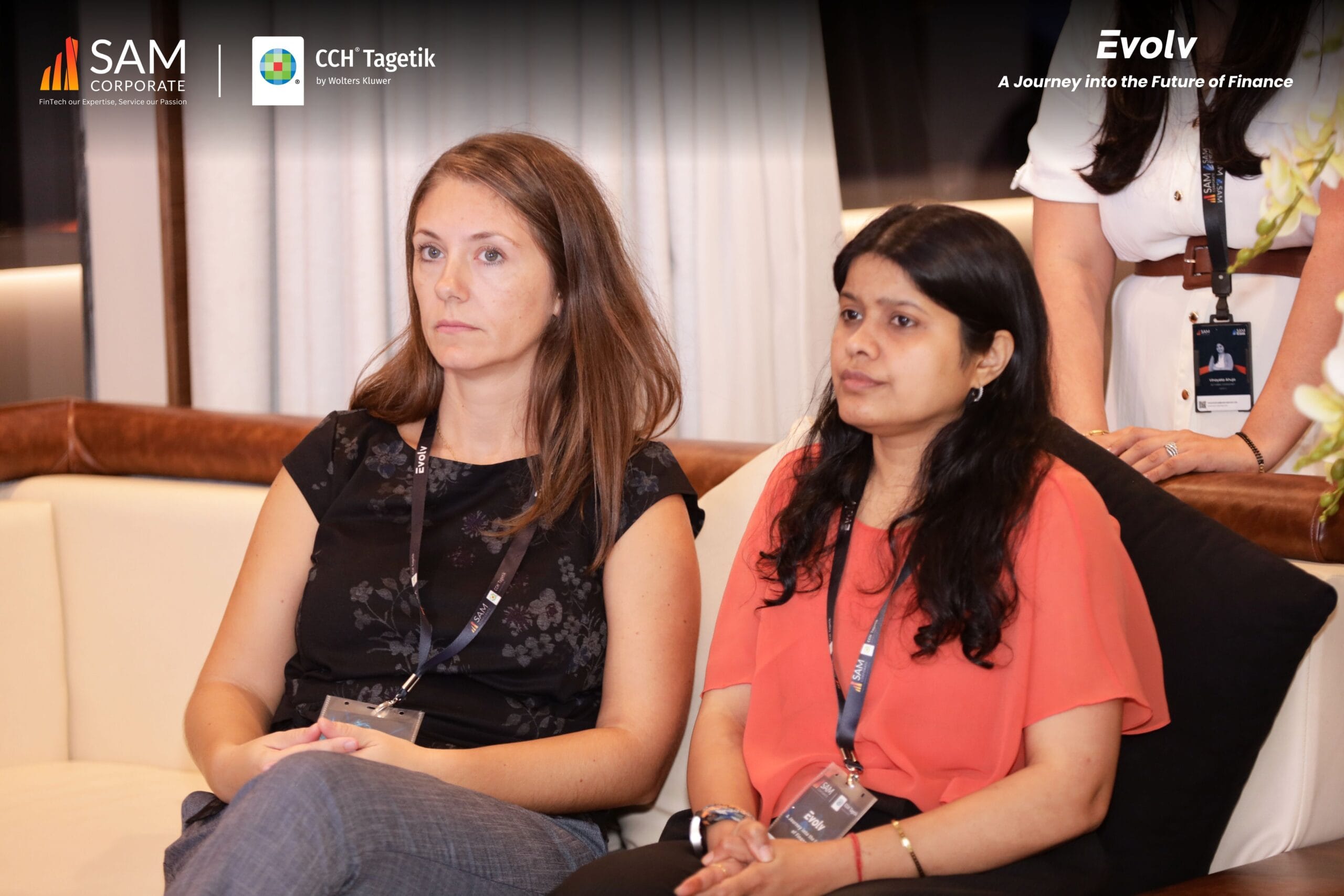 Two female finance executives seated on a couch listening to a session at the Evolv event by SAM Corporate and CCH Tagetik.