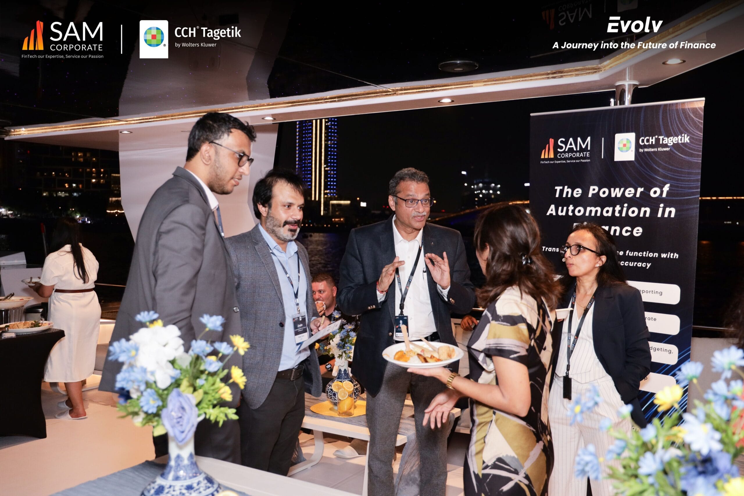 An executive greeting a group of guests on the yacht deck at the Evolv networking event by SAM Corporate and CCH Tagetik.