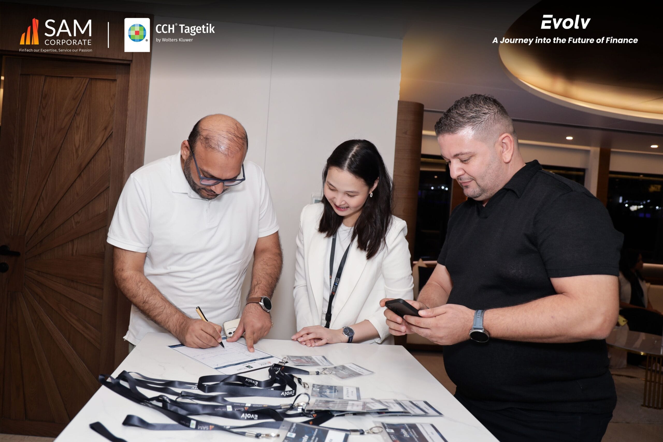 Event staff assisting a finance professional with sign-in at the registration area of the Evolv summit by SAM Corporate and CCH Tagetik.