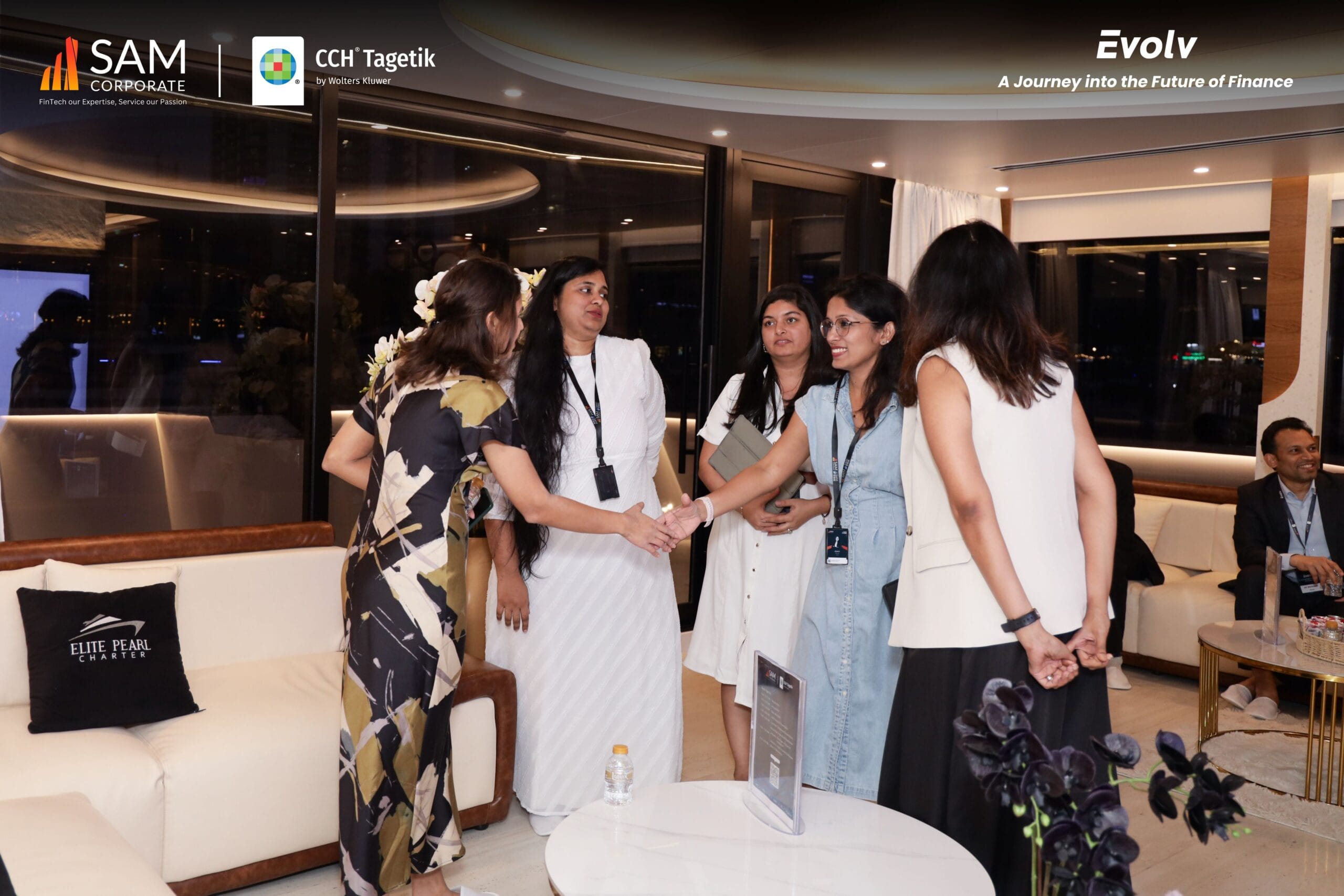 Women professionals shaking hands and networking at the Evolv event, co-sponsored by SAM Corporate and CCH Tagetik.