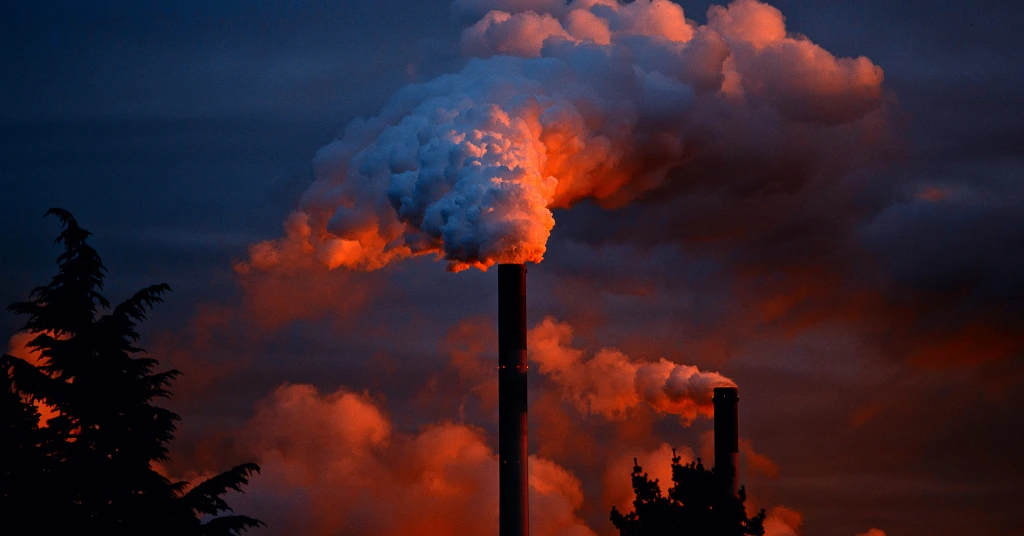 Industrial cooling towers and smokestacks emitting steam and smoke against a blue sky and sunset, with text regarding IPSASB Climate-Related Reporting Standards for the public sector.