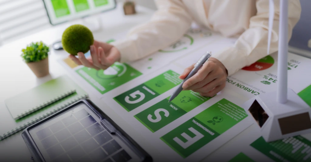 A professional analyzing ESG reports and charts on a desk, holding a moss-covered ball representing environmental sustainability and corporate responsibility.