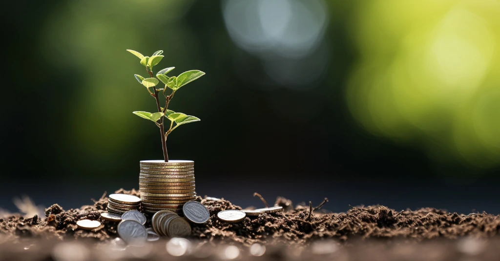 Green sprout growing from a stack of coins representing green finance growth.