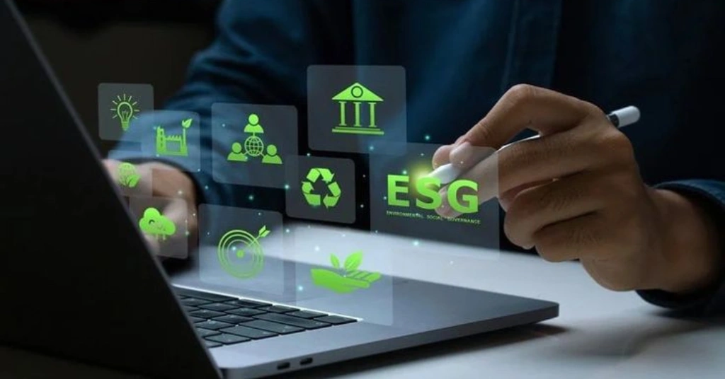 Professional using a laptop and stylus to manage digital ESG icons for environmental and social governance.